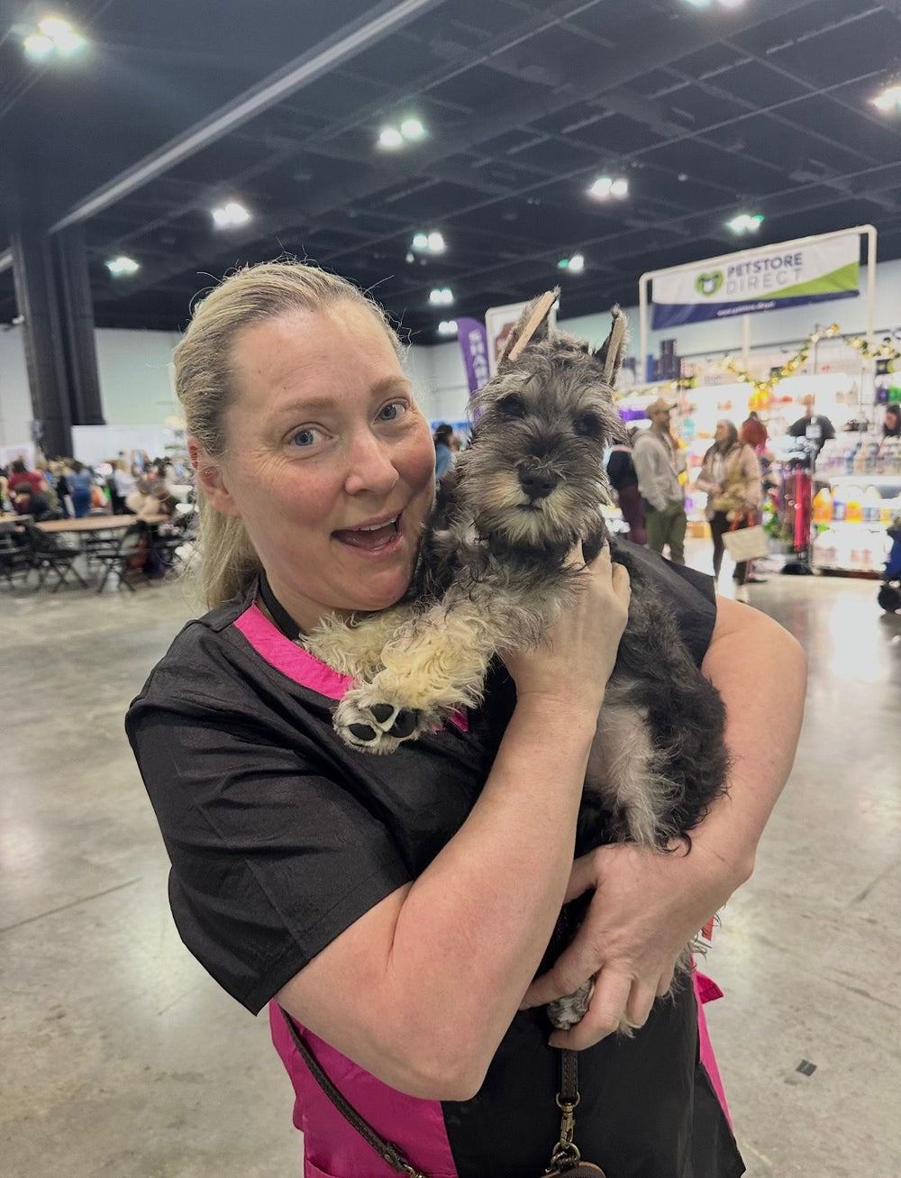 Kristy at a professional grooming expo holding a schnauzer puppy